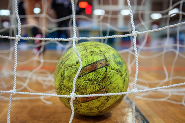 Handbal bal in netten. Onscherpe achtergrond van Hof en atleten. Close-up. — Stockfoto