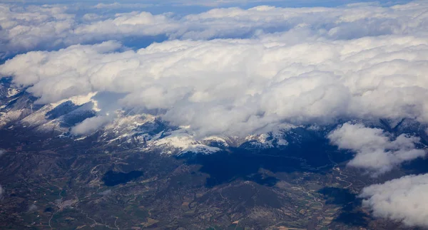 White heavy clouds background hanging on blue sky over mountain. Aerial photo from plane's window. — Stock Photo, Image