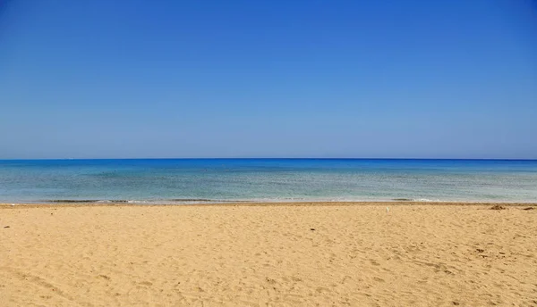 Sandy beach, calm sea, clear blue sky background. Summer destination. — Stock Photo, Image
