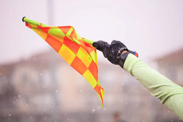 Assistente árbitro de futebol de futebol levanta a bandeira. Desfocado fundo nevado — Fotografia de Stock