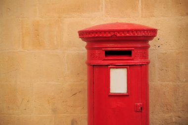 Geleneksel, İngiliz postbox kırmızı renkte. Mektupları alan posta kutusu. Arka plan için hafif portakal kireçtaşı duvar. Boşaltmak, görünümü kadar yakın.