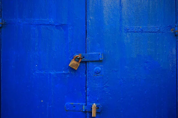 Podłoże drewniane niebieskie drzwi zablokowane z dwie zardzewiałe kłódki. Wieku, zamknięte wejście, zamknąć widok szczegółów. — Zdjęcie stockowe