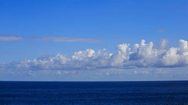 A ship is traveling in calm sea to an exotic destination. Blue sky with fluffy clouds background. — Stock Photo, Image