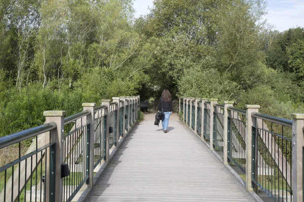 Mujer caminando sobre puente de madera — Foto de Stock