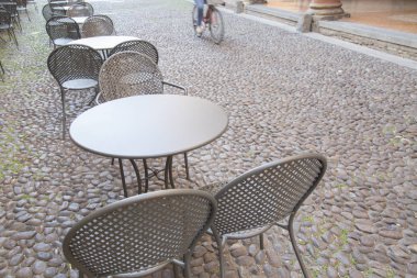Cafe masa ve sandalyeler ile bisikletçi Arnavut kaldırımlı sokakta, Bologn