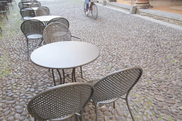 Cafe masa ve sandalyeler ile bisikletçi Arnavut kaldırımlı sokakta, Bologn