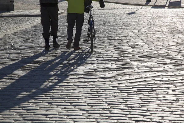 Cyclist and Pedestrian on Cobblestone Street in Stockholm