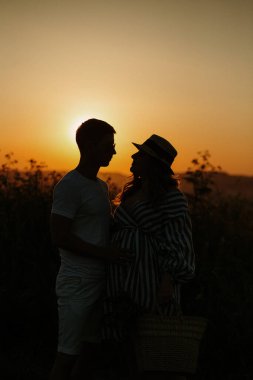 Gün batımında romantik bir çift. Siluet öpücüğü.