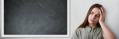 Okul ve eğitim kavramı. Uzun siyah saçlı ayakta yakınındaki dersleri yorgun eliyle başını tutan blackboard ile güzel akıllı kız öğrenci portresi