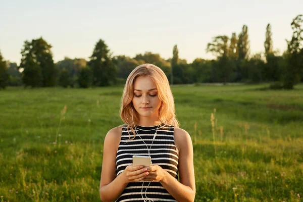 Portrait de fille aux cheveux blonds avec son téléphone portable et ses écouteurs — Photo