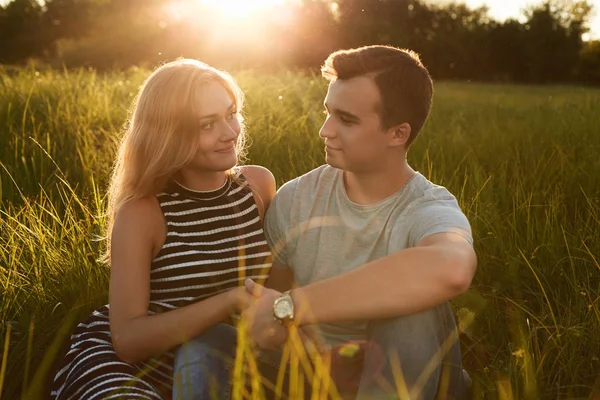 Jeune couple heureux assis ensemble sur l'herbe tenant leurs mains — Photo