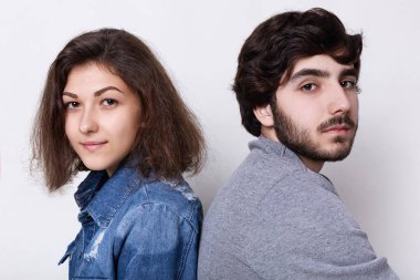 Bir kıllı adam ve esmer kadın ev ciddi bir ifadeyle kameraya bakıyor sırt sırta rahatlatıcı oturuyordu. Birbirine yakın oturan genç hipsters. Aşk ve ilişkiler kavramı