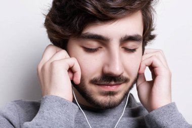 Bir close-up kulaklıklar üzerinde ellerini tutarak gözleri kapalı onun kulaklık ile müzik dinleme koyu saç ve sakal enjoing şık bir adamla. Üzerinden müzik dinleme keyfi. 