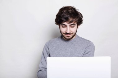 İnternette bir şey için arama ekranında sürpriz arıyor onun laptop ile oturan rahat kıyafetler giymiş gülümseyen yakışıklı çocuk portresi. İletişim, yaşam tarzı, insanlar