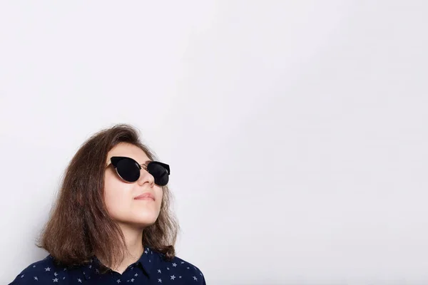 Mode- und Stilkonzept. eine elegante junge Brünette mit Sonnenbrille, die isoliert über weißem Hintergrund nach oben schaut. Porträt eines attraktiven jungen Models mit Sonnenbrille — Stockfoto