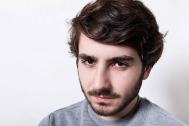 Gözleri şaşı yakışıklı hipster Siyah sakallı ve şık saç kameraya ciddi bir yüz ifadesiyle arıyor headshot. Erkeklik portresi. İnsanlar ve duygular.