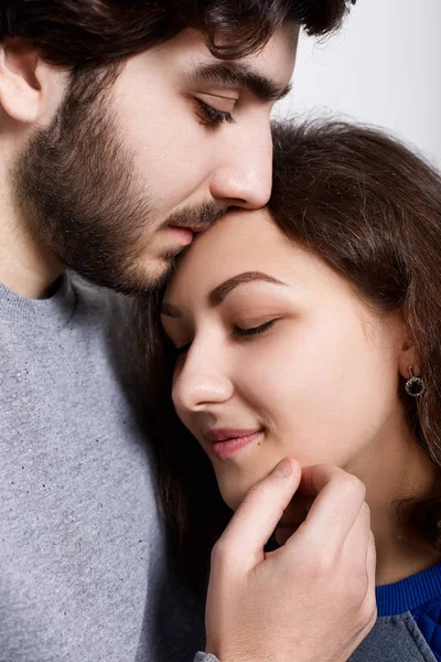 Uma foto sensual de casal amoroso de pé perto um do outro. Uma jovem inclinada para o namorado. Um hipster barbudo a tocar a testa da namorada com os lábios. Sentimentos e relacionamentos . — Fotografia de Stock