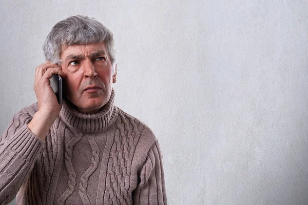 A horizontal portrait of serious, worried, upset mature man talkiing on cellphone. An old employee deciding some problems over telephone. Human face expression emotion, reactions, life perception — Stock Photo, Image