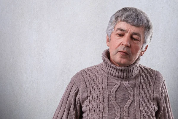 Un triste uomo anziano dall'aspetto premuroso vestito di maglione. Un uomo anziano rugoso con i capelli grigi pensando alla sua vita avendo un'espressione pensierosa e triste isolata su sfondo bianco — Foto Stock