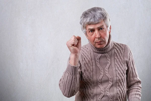 A handsome mature man showing his fist while being angry and irritated. A senior man with wrinkles showing his dissatisfaction with gesture. Facial expressions, emotions, feelings and people concept. — Stock Photo, Image