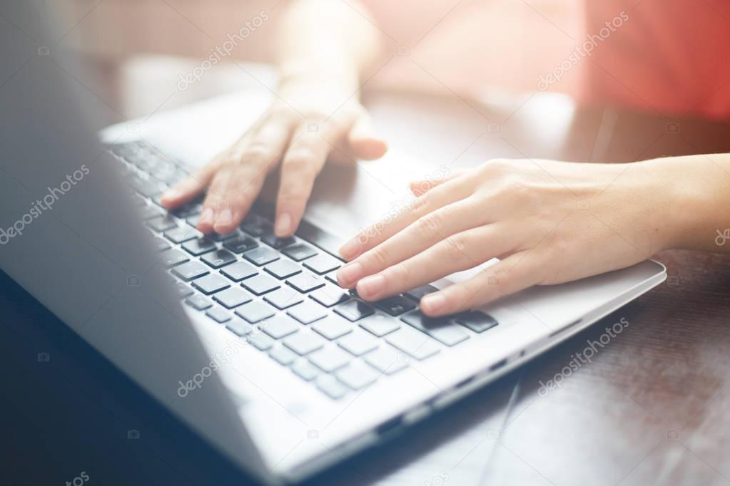 People and modern technology concept. Close up shot of female hands typing on keyboard of her laptop. Young businesswoman working on notebook computer at office. Female freelancer typing messages 