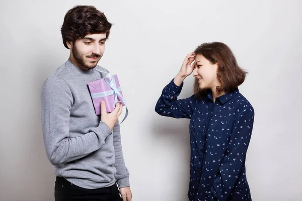 Uma foto de dois verdadeiros amigos. Um cara elegante vai presentear seu amigo com um presente. Uma jovem feliz vai receber um presente. Um jovem hipster segurando uma caixa de presente em suas mãos . — Fotografia de Stock