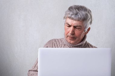Önünde diz üstü ifade ve kırışıklıklar yüzünde beyaz arka plan üzerinde izole memnun gri saç siting ile olgun bir erkek. İnsanlar, duygular, teknoloji ve yaşam tarzı kavramı.