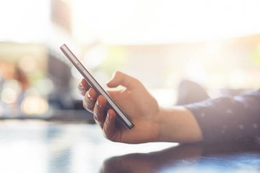 A cep telefonu mesajları gönderme tutan kadının el ile kapatın. Smartphone manifatura bir şey tutan genç kadın. Teknoloji kavramı.