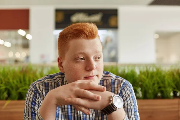 A vízszintes portré szeplős vörös hajú fiú visel kockás inget és elegáns karóra, zöld ültetvények tartja a kezet együtt látszó félre várva, hogy valaki ül. — Stock Fotó