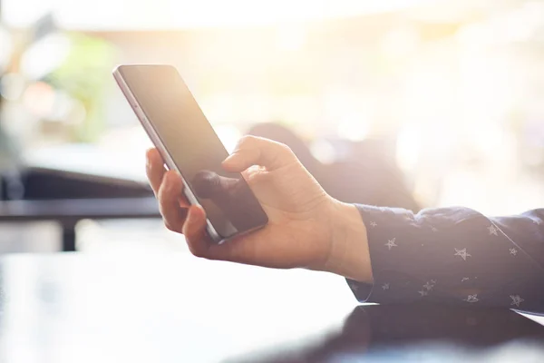 Cortado tiro de las manos de la mujer sosteniendo el teléfono celular haciendo compras en línea. Efectos visuales. Mujer usando el teléfono móvil mientras está sentado en la mesa de madera. Concepto de tecnología y personas . —  Fotos de Stock