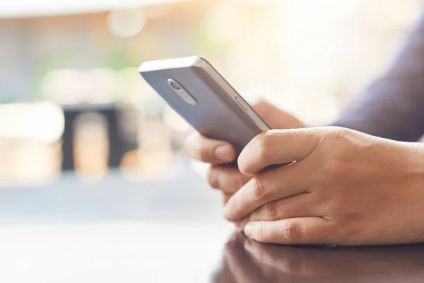 Beskuren bild av kvinnans händer som håller mobiltelefon kontrollera hennes e-post online i café med höghastighetsanslutning till internet. Teknik och kommunikation koncept. — Stockfoto