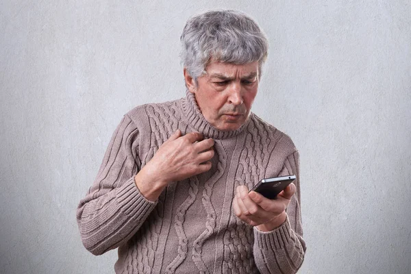 Портрет літнього чоловіка з сірим волоссям, який шокував вираз, дивлячись у його повідомлення для читання смартфона. Чоловік дивиться жахливе відео онлайн за допомогою мобільного телефону . — стокове фото