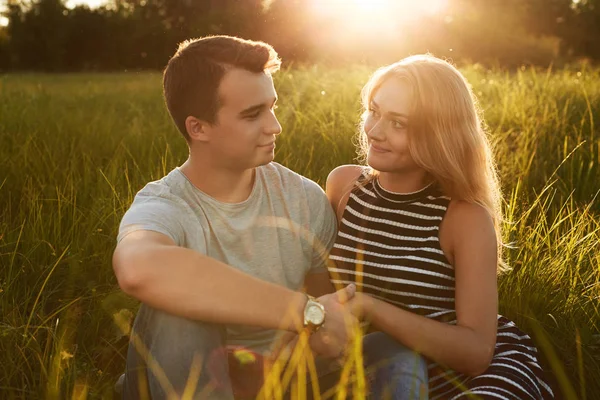 Pasangan muda yang bahagia duduk bersama di rumput — Stok Foto