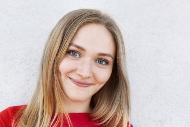 Mavi gözlü, ince dudaklar ve mutlu bir şekilde beyaz bankamatik izole kamera bakarak onun yanaklarda gamzeli güzel çilli kadının kapatın. Kamera poz kırmızı giysili genç ve güzel kızı