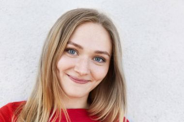 Mavi gözlü, ince dudaklar ve mutlu bir şekilde beyaz bankamatik izole kamera bakarak onun yanaklarda gamzeli güzel çilli kadının kapatın. Kamera poz kırmızı giysili genç ve güzel kızı