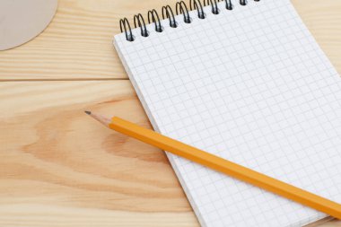 Boş spiral defter kalem ahşap masanın üzerinde döşeme ile. Modern tasarım ev büro masa boş Not Defteri sayfası. Üstten Görünüm, düz yatıyordu. Boş sayfa metin veya adverisment için. Eğitim kavramı
