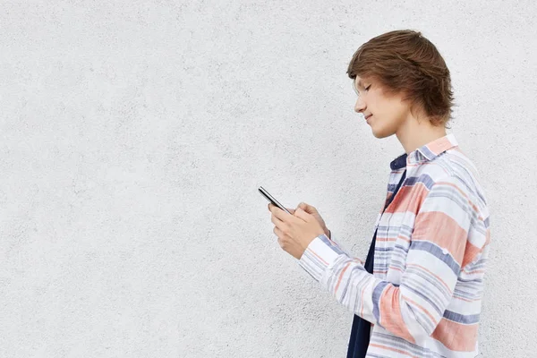 Elegante adolescente de pie de lado sosteniendo el teléfono celular aislar — Foto de Stock