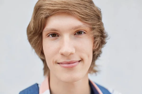 Primer plano retrato de niño guapo con peinado elegante, ojos oscuros y estrechos, labios delgados, piel sana pura y hoyuelo en la mejilla mirando directamente a la cámara que tiene una expresión seria. Gente, belleza —  Fotos de Stock