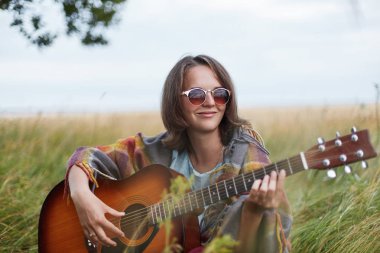 Mutlu kadın hayatında keyifli anlar hatırlayarak gitar çalmak doğa ile yalnız olmak. Genç ve güzel kadın Grönland oturan güneş gözlüğü takıyor mutlu ifade ile mesafe bakarak