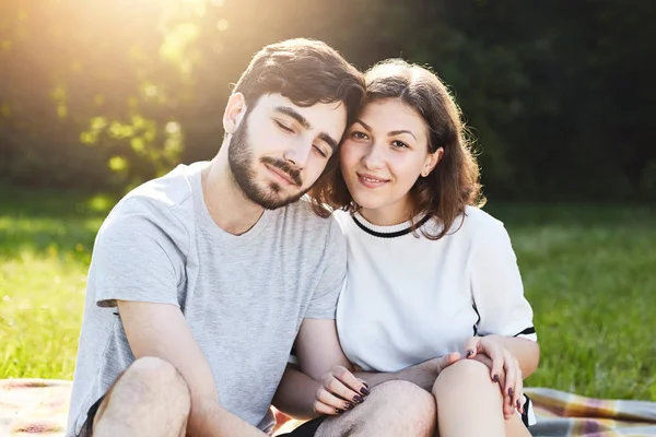 Casal romântico sentado perto um do outro enquanto descansa ao ar livre na natureza durante o dia de verão, sentindo felicidade e relaxamento. Pessoas, amor, relacionamentos, harmonia e conceito de união — Fotografia de Stock