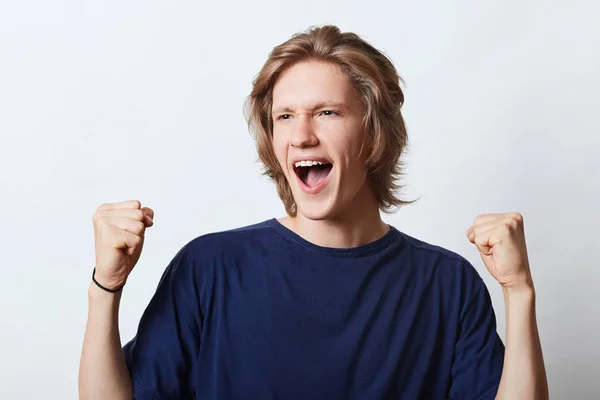Successful male with happy expression, clenching fists with triumph, rejoicing his success at work. Happy male student being glad to pass exams successfully. People, happiness and joy concept — Stock Photo, Image