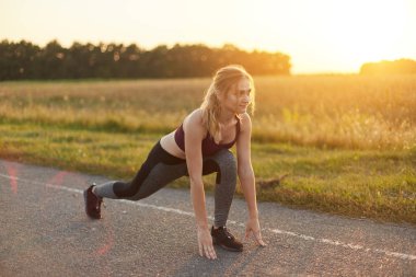 Çekici Bayan spor ayakkabı ve giyim, yolda karşı günbatımı, sevme jimnastik, spor egzersizleri yapıyor bacaklarını germe. Sahip sağlıklı yaşam için spor, içeri aktif genç kız