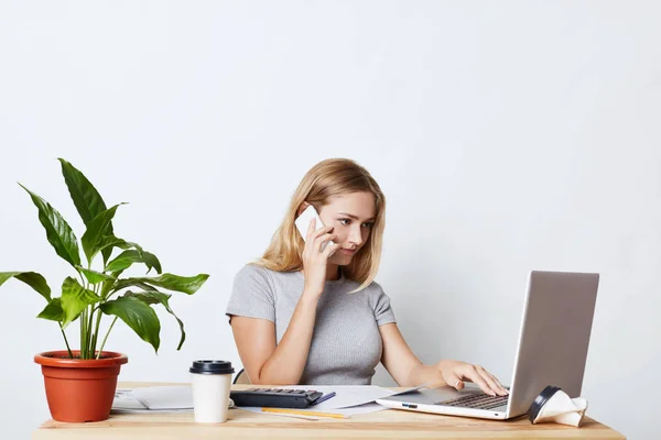 Wanita pengusaha, sibuk dengan pekerjaan, keyboarding di komputer laptop, menelepon mitra bisnisnya sambil berkonsultasi sesuatu. Wanita muda pekerja lepas bekerja dengan teknologi modern saja — Stok Foto