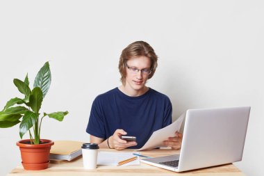 Başarılı bir iş adamı kağıt işi yapar, mali, akıllı telefonunuzda alır ileti analiz eder. Genç adam elektronik cihazlar ve kağıtları, büyük iş ve kariyer yapma dahil ile çevrili