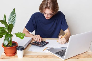 Mali ve ödemeler genel kavram. Yakışıklı adam mali sorunları ile ilgilenir, borçlarını hesaplar, beyaz arka plan üzerinde izole açılan laptop önünde oturur. Erkek masada oturur olarak bütçe Anasayfa