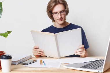 Akıllı zor çalışma şık erkek öğrenci gözlük takıyor, özenli bakışları defterinde var., makale okumak dahil olmak, yazmadan önce bilimsel literatür okur ve iş. Eğitim kavramı