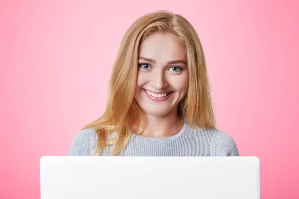 Χαρούμενα θηλυκά μοντέλο με χαμόγελα ευτυχισμένη έκφραση χρησιμοποιεί gladfully, φορητό υπολογιστή, surf κοινωνικά δίκτυα και λαμβάνει μηνύματα από φίλους, χρησιμοποιεί ασύρματη σύνδεση στο internet. Τεχνολογία έννοια — Φωτογραφία Αρχείου