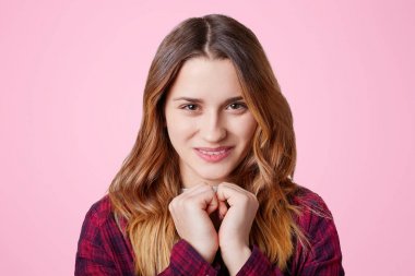 Görünüm çekici ile olumlu çekici kadın eller birlikte hoş bir şey bekliyor gibi tutar veya mevcut almak, pembe studio arka plan üzerinde izole rahat kareli gömlek giyer