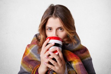 Sevimli genç kız içinde ekose kaplı dışında soğuk kış günü sırasında yürüyüş içecekler sonra sıcak kahve veya çay, beyaz arka plan üzerinde izole kendini ısıtmak çalışır. Rahat bir atmosfer. Kış, insanlar kavramı