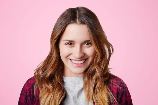 Alegre modelo femenino de aspecto agradable tiene una sonrisa brillante con dientes blancos perfectos, incluso, contento de recibir el cumplido de novio, aislado sobre fondo rosa. Concepto de felicidad y belleza — Foto de Stock